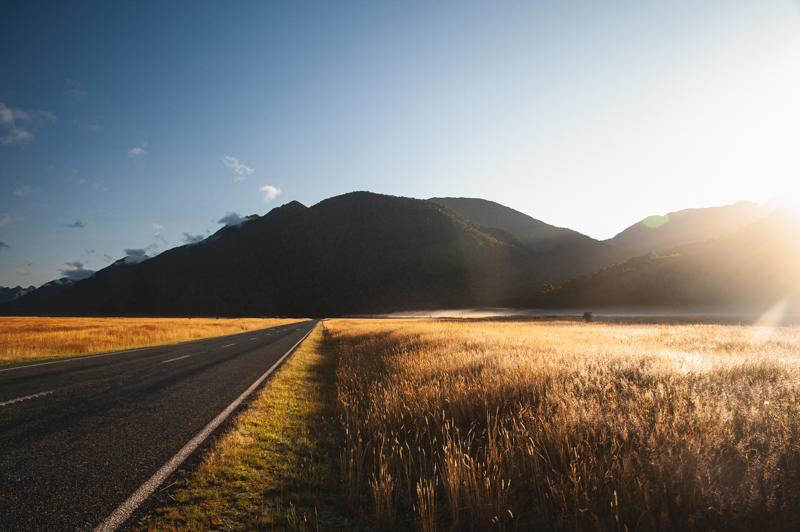 First mornings light cresting over a mountain illuminating the road to Milford Sound