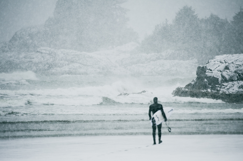 A surfer heads out into the snow for a winter surf session